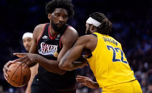 Philadelphia 76ers' Joel Embiid, left, drives to the basket against Indiana Pacers' Isaiah Jackson, right, during the first half of an NBA basketball game, Friday, Dec. 12, 2025, in Philadelphia. (AP Photo/Chris Szagola)