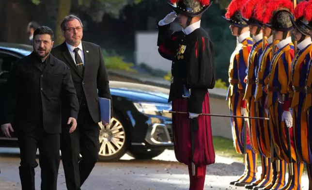 Ukraine President Volodymyr Zelenskyy, left, walks past Swiss guards as he arrives to meet with Pope Leo XIV in Castel Gandolfo, Italy, Tuesday, Dec. 9, 2025. (AP Photo/Andrew Medichini)