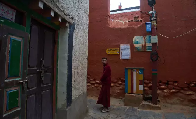A Buddhist monk walks in an alley as a CCTV camera mounted on a pole watches over the area in the ancient ethnic Tibetan city of Mustang, Nepal, April 18, 2025. (AP Photo/Niranjan Shrestha)