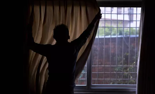 A Tibetan living in exile pulls the curtain before he gives an interview in Kathmandu, Nepal, April 14, 2025. (AP Photo/Niranjan Shrestha)