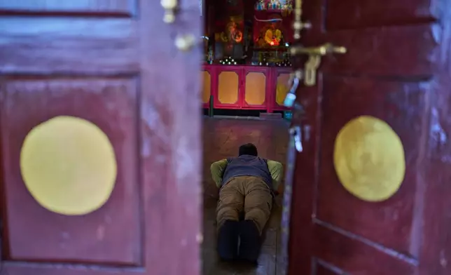 A Tibetan exile offers a prayer, seen through the door of a monastery, at a Tibetan refugee camp in Mustang, Saturday, April 19, 2025. (AP Photo/Niranjan Shrestha)