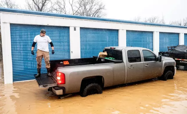 A man rides in a pick-up truck bed while salvaging belongings from a flooded storage unit following heavy rains on Monday, Dec. 22, 2025, in Redding, Calif. (AP Photo/Noah Berger)