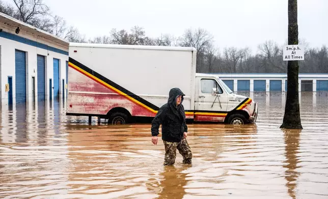 Dekoda Cruz walks through flood water while helping a friend who's tire shop flooded during heavy rains on Monday, Dec. 22, 2025, in Redding, Calif. (AP Photo/Noah Berger)