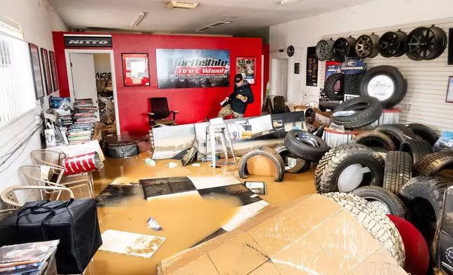 Dekoda Cruz walks through the flooded office of Northstate Tire &amp; Wheel following heavy rains on Monday, Dec. 22, 2025, in Redding, Calif. (AP Photo/Noah Berger)