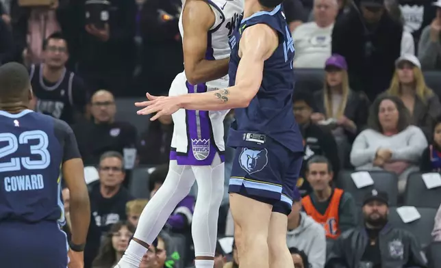 Sacramento Kings forward Keegan Murray, left, attempts to dunk on Memphis Grizzlies center Zach Edey during the first half of an NBA basketball game Sunday, Nov. 30, 2025, in Sacramento, Calif. (AP Photo/Sara Nevis)