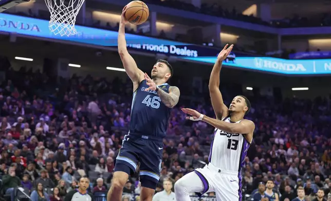 Memphis Grizzlies guard John Konchar (46) makes a layup on a fast break with Sacramento Kings forward Keegan Murray (13) defending during the first half of an NBA basketball game Sunday, Nov. 30, 2025, in Sacramento, Calif. (AP Photo/Sara Nevis)