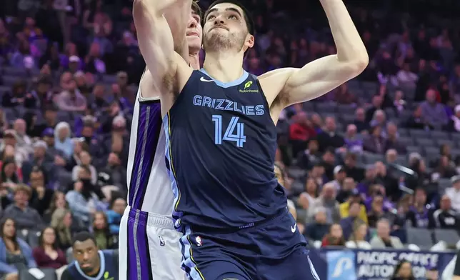 Memphis Grizzlies center Zach Edey (14) goes up for a layup with Sacramento Kings center Maxime Raynaud, left, defending during the first half of an NBA basketball game, Sunday, Nov. 30, 2025, in Sacramento, Calif. (AP Photo/Sara Nevis)