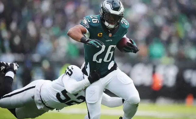 Philadelphia Eagles running back Saquon Barkley (26) is brought down by Las Vegas Raiders outside linebacker Elandon Roberts (52) during the first half of an NFL football game Sunday, Dec. 14, 2025, in Philadelphia. (AP Photo/Matt Slocum)