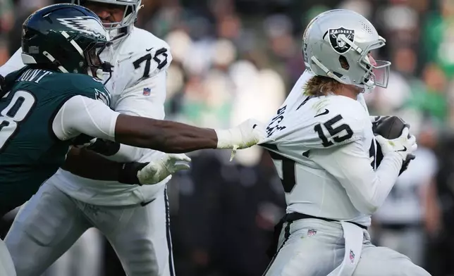 Philadelphia Eagles linebacker Jalyx Hunt (58) grabs Las Vegas Raiders quarterback Kenny Pickett (15) during the second half of an NFL football game Sunday, Dec. 14, 2025, in Philadelphia. (AP Photo/Matt Slocum)