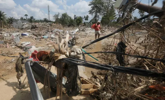 A survivor carries a bag of salvaged items at an area devastated by flash flood in Aceh Tamiang on Sumatra Island, Indonesia, Friday, Dec. 5, 2025. (AP Photo/Binsar Bakkara)