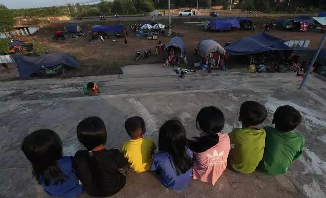 Children sit near tents in Srey Snam, Siem Reap province, after fleeing from their homes with their families at Cambodia's border with Thailand, Tuesday, Dec. 9, 2025. (AP Photo/Heng Sinith)
