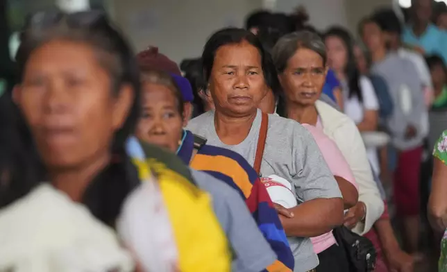 Thai residents who fled their homes following clashes between Thai and Cambodian soldiers line up for food distribution at an evacuation center in Surin province, Thailand, Tuesday, Dec. 9, 2025. (AP Photo/Sakchai Lalit)