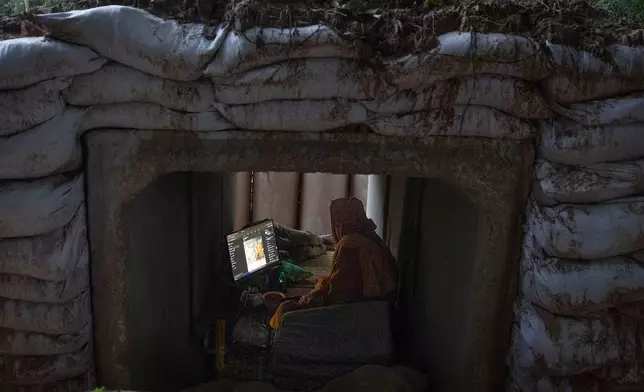 A Thai Buddhist monk uses his computer while taking shelter in Buriram province, Thailand, Tuesday, Dec. 9, 2025, after he fled clashes between Thai and Cambodian soldiers. (AP Photo/Wason Wanichakorn)