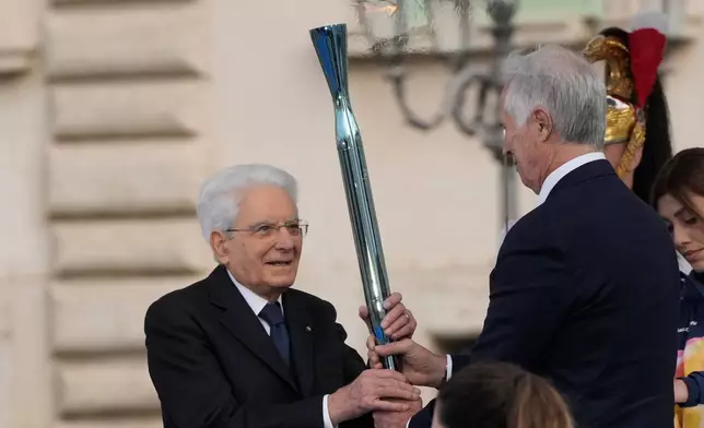 Organizing Committee President Giovanni Malagò passes the torch to the Italian President Sergio Mattarella during the Milan Cortina 2026 Winter Olympics cauldron lighting in front of the Quirinale Presidential Palace, in Rome, Friday Dec. 5, 2025. (AP Photo/Gregorio Borgia)