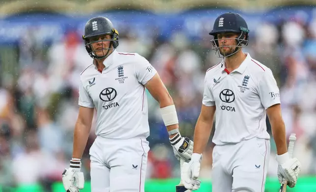 England's Jamie Smith, left, and Will Jacks walk from the field as rain delays play on the final day of the third Ashes cricket test between England and Australia in Adelaide, Australia, Sunday, Dec. 21, 2025. (AP Photo/James Elsby)
