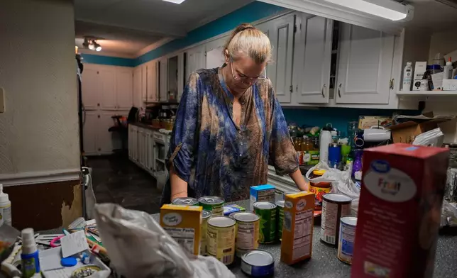 FILE - Goldie Getter, the wife of a civil service employee who was furloughed due to the government shutdown, unpacks groceries her husband received from a food bank, in Gulfport, Miss., Monday, Nov. 3, 2025. (AP Photo/Gerald Herbert, File)