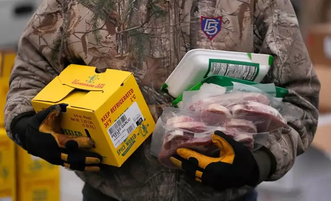 FILE - A Utah Food Bank volunteer carries groceries at a mobile food pantry distribution site Dec. 21, 2022, in Salt Lake City. (AP Photo/Rick Bowmer, File)