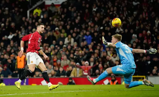 Manchester United's Diogo Dalot, left, makes an attempt on goal as Newcastle's goalkeeper Aaron Ramsdale reaches out for a save during the English Premier League soccer match between Manchester United and Newcastle in Manchester, England, Friday, Dec. 26, 2025. (AP Photo/Dave Thompson)