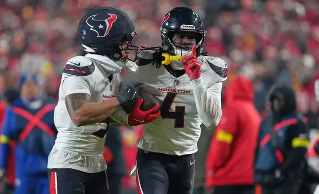 Houston Texans cornerback Kamari Lassiter (4) is congratulated by teammate Jalen Pitre, left, after intercepting a pass during the second half of an NFL football game against the Kansas City Chiefs Sunday, Dec. 7, 2025, in Kansas City, Mo. (AP Photo/Ed Zurga)