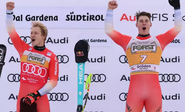 Switzerland's Franjo von Allmen, right, winner of an alpine ski, men's World Cup downhill, celebrates on the podium with second-placed Switzerland's Marco Odermatt, in Val Gardena, Italy, Saturday, Dec. 20, 2025. (AP Photo/Alessandro Trovati)