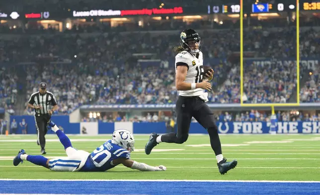Jacksonville Jaguars quarterback Trevor Lawrence (16) scores past Indianapolis Colts safety Nick Cross (20) during the first half of an NFL football game Sunday, Dec. 28, 2025, in Indianapolis. (AP Photo/AJ Mast)