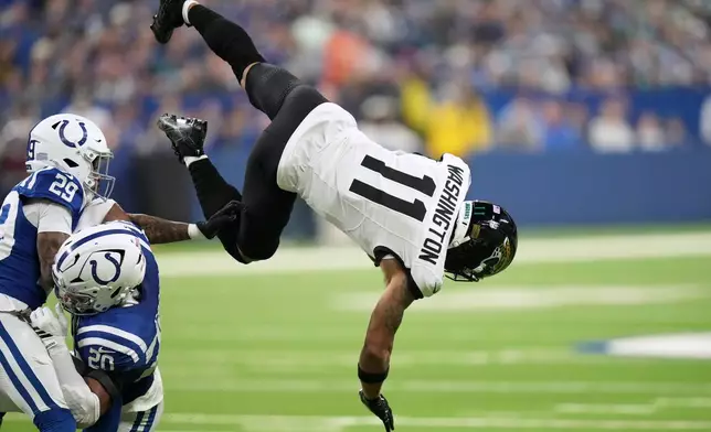 Jacksonville Jaguars wide receiver Parker Washington (11) catches a pass as Indianapolis Colts cornerback Mekhi Blackmon (29) and safety Nick Cross (20) defend during the first half of an NFL football game Sunday, Dec. 28, 2025, in Indianapolis. (AP Photo/AJ Mast)