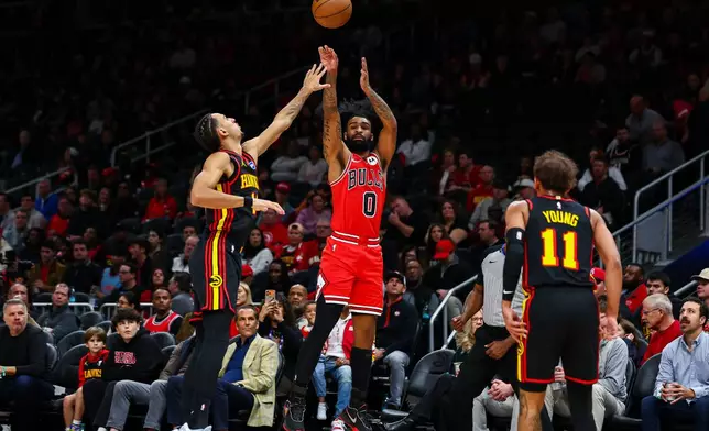 Chicago Bulls guard Coby White (0) shoots over Atlanta Hawks forward Zaccharie Risacher, left, during the first half of an NBA basketball game, Sunday, Dec. 21, 2025, in Atlanta. (AP Photo/Colin Hubbard)