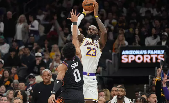 Los Angeles Lakers forward Lebron James (23) looks to shoot over Phoenix Suns forward Ryan Dunn (0) during the first half of an NBA basketball game, Sunday, Dec. 14, 2025, in Phoenix. (AP Photo/Rick Scuteri)