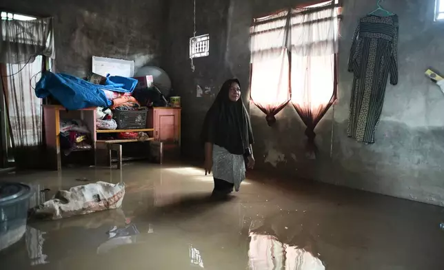 A woman stands inside her flooded house in Pidie Jaya, Aceh province, Indonesia, Wednesday, Dec. 3, 2025. (AP Photo/Reza Saifullah)
