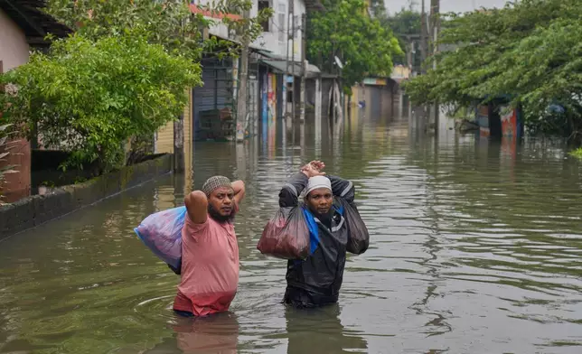 Flood victims wade through water in Colombo, Sri Lanka, Saturday, Nov, 29, 2025. (AP Photo/Eranga Jayawardena)