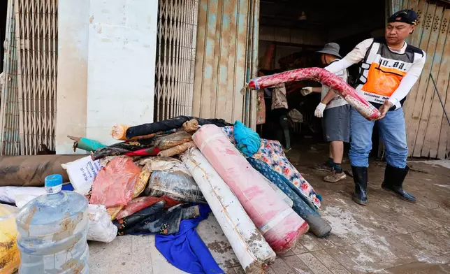 Volunteers move rolls of fabric damaged from floods in Songkhla province, southern Thailand, Sunday, Nov. 30, 2025. (AP Photo/Sarot Meksophawannakul)