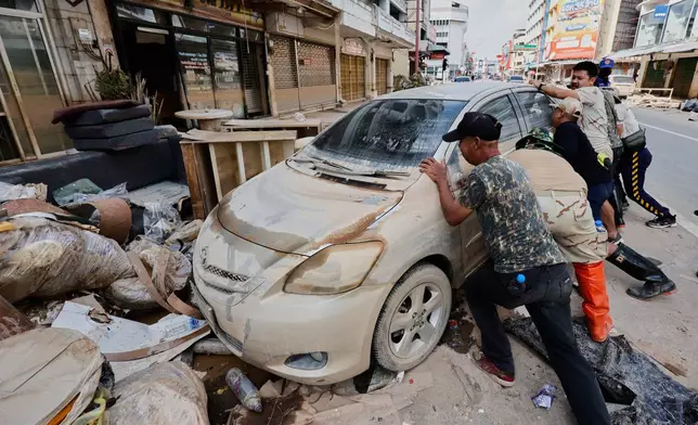 Peoples move a car damaged from floods in Songkhla province, southern Thailand, Sunday, Nov. 30, 2025. (AP Photo/Sarot Meksophawannakul)