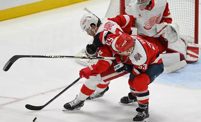 Detroit Red Wings defenseman Ben Chiarot, left, battles for the puck against Washington Capitals center Ethen Frank in front of Red Wings goaltender John Gibson during the third period of an NHL hockey game, Saturday, Dec. 20, 2025, in Washington. (AP Photo/John McDonnell)