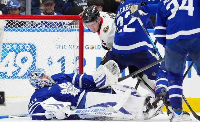 Ottawa Senators left wing Brady Tkachuk (7) knocks Toronto Maple Leafs goaltender Joseph Woll (60) to the ice during the second period of an NHL hockey game in Toronto, Saturday, Dec. 27, 2025. (Frank Gunn/The Canadian Press via AP)