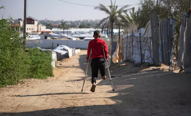 Fadi al-Balbisi, 12, whose right leg was amputated after a shell fired by the Israeli army on April 28, walks on crutches back home after receiving rehabilitation training with a prosthetic leg at Hamad Hospital in Zawaida, central Gaza Strip, Thursday, Dec. 4, 2025. (AP Photo/Abdel Kareem Hana)