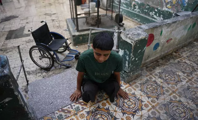 Youssef al-Samri, 16, who lost his legs while fetching water near his home after an Israeli airstrike in May, walks on his hands in the kindergarten where he was displaced in the Al-Tuffah neighborhood, Gaza City, Monday, Nov. 24, 2025. (AP Photo/Abdel Kareem Hana)