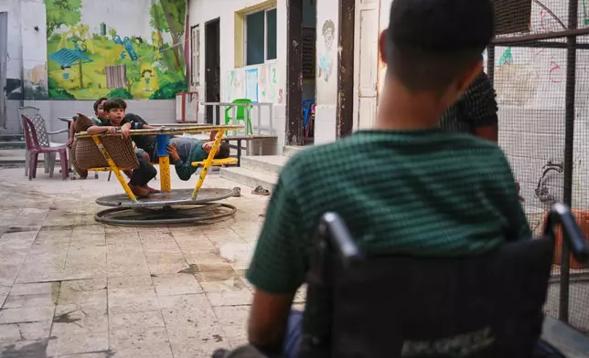 Youssef al-Samri, 16, who lost his legs while fetching water near his home after an Israeli airstrike in May, sits in a wheelchair in the playground of the kindergarten where he was displaced in the Al-Tuffah neighborhood, Gaza City, Monday, Nov. 24, 2025. (AP Photo/Abdel Kareem Hana)