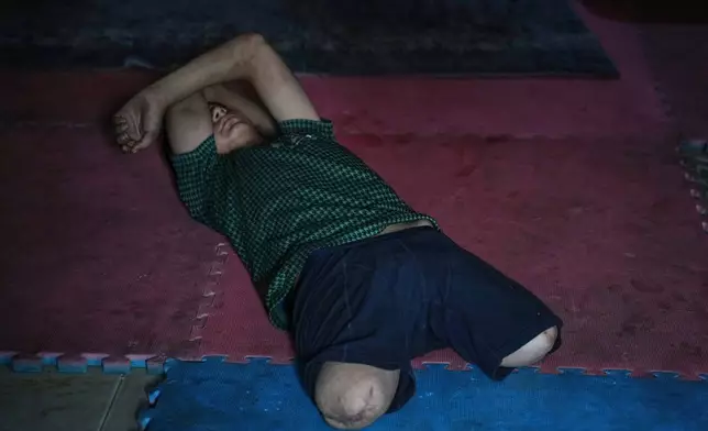 Youssef al-Samri, 16, who lost his legs while fetching water near his home after an Israeli airstrike in May, lies on the floor of a classroom in the kindergarten where he was displaced in the Al-Tuffah neighborhood, Gaza City, Monday, Nov. 24, 2025. (AP Photo/Abdel Kareem Hana)