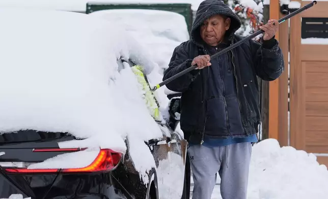 A person cleans the snow off of a car during a cold day in Wheeling, Ill., Tuesday, Dec. 2, 2025. (AP Photo/Nam Y. Huh)