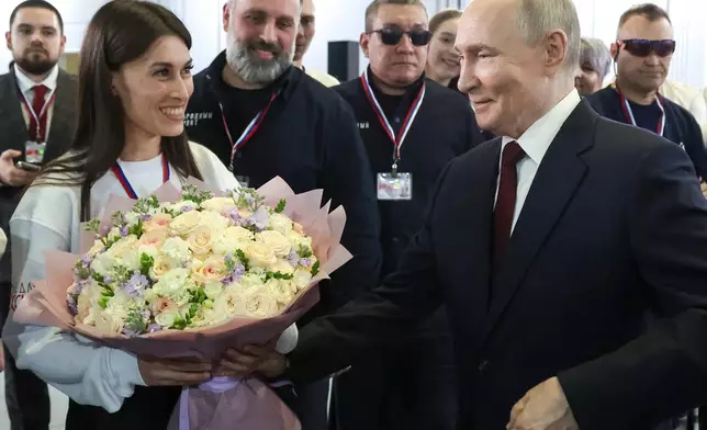 Russian President Vladimir Putin, right, thanks a group of volunteers who worked preparing his call-in show at Gostinny Dvor, in Moscow, on Friday, Dec. 19, 2025. (Alexander Kazakov, Sputnik, Kremlin Pool Photo via AP)