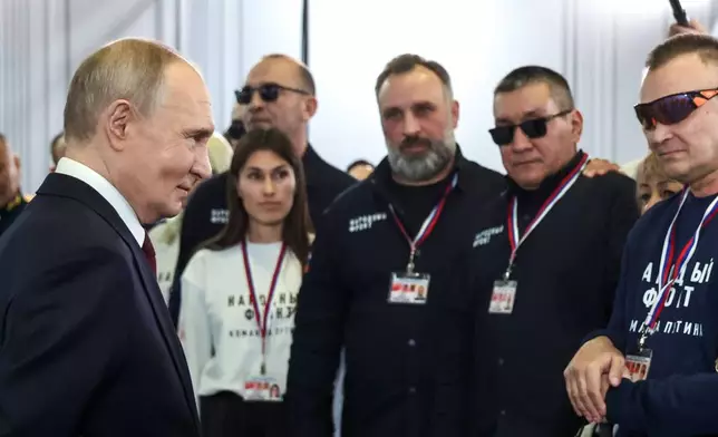 Russian President Vladimir Putin, left, thanks a group of volunteers who worked preparing his call-in show at Gostinny Dvor, in Moscow, on Friday, Dec. 19, 2025. (Alexander Kazakov, Sputnik, Kremlin Pool Photo via AP)