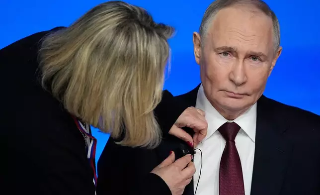 A TV assistant attaches a microphone to Russian President Vladimir Putin's suit prior to his annual news conference and call-in show at Gostinny Dvor, in Moscow, on Friday, Dec. 19, 2025. (AP Photo/Pavel Bednyakov)