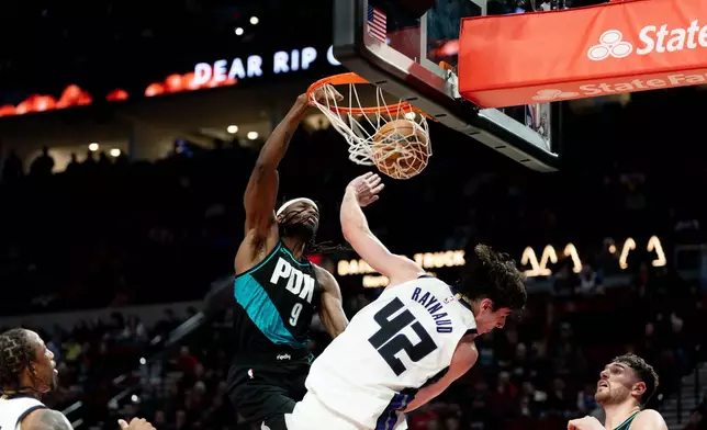 Portland Trail Blazers forward Jerami Grant, left, dunks the ball against Sacramento Kings center Maxime Raynaud, right, during the second half of an NBA basketball game Thursday Dec. 18, 2025, in Portland, Ore. (AP Photo/Howard Lao)