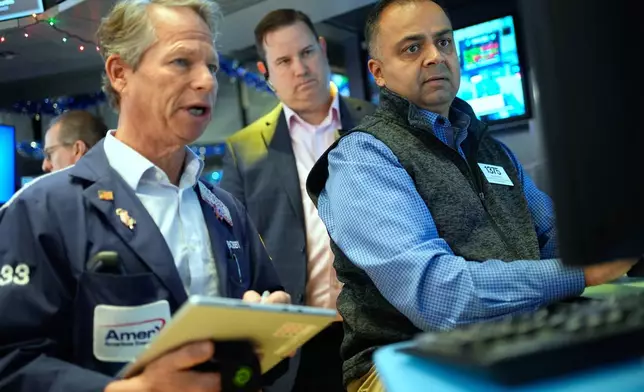 Dilip Patel, right, and Bobby Charmak, left, work on the floor at the New York Stock Exchange in New York, Wednesday, Dec. 10, 2025. (AP Photo/Seth Wenig)