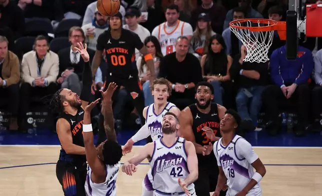 New York Knicks guard Jalen Brunson, left, shoots over Utah Jazz defenders during the second half of an NBA basketball game, Friday, Dec. 5, 2025, in New York. (AP Photo/Heather Khalifa)