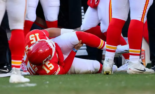 Kansas City Chiefs quarterback Patrick Mahomes grabs his knee after being injured during the second half of an NFL football game against the Los Angeles Chargers, Sunday, Dec. 14, 2025 in Kansas City, Mo. (AP Photo/Reed Hoffmann)