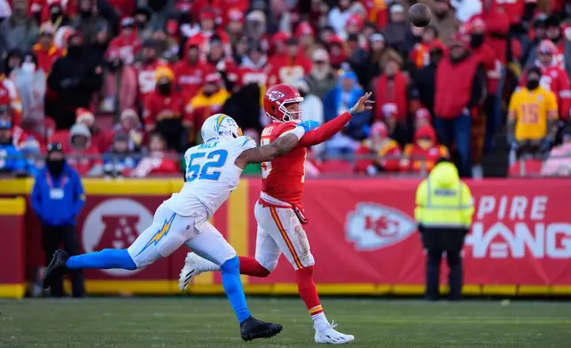 Kansas City Chiefs quarterback Patrick Mahomes, right, throws the ball away under pressure from Los Angeles Chargers outside linebacker Khalil Mack (52) during the second half of an NFL football game Sunday, Dec. 14, 2025, in Kansas City, Mo. (AP Photo/Charlie Riedel)