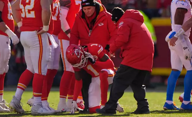 Kansas City Chiefs wide receiver Xavier Worthy (1) is checked on after being injured during the first half of an NFL football game against the Los Angeles Chargers Sunday, Dec. 14, 2025, in Kansas City, Mo. (AP Photo/Charlie Riedel)