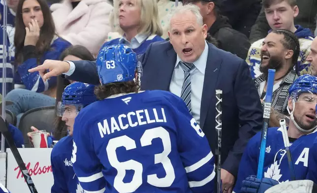 Toronto Maple Leafs head coach Craig Berube talks to forward Matias MacCelli (63) during second period NHL hockey action against the Pittsburgh Penguins in Toronto on Tuesday, Dec. 23, 2025. (Nathan Denette/The Canadian Press via AP)