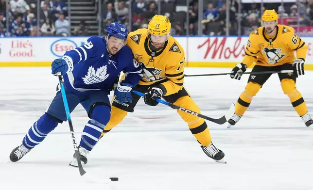 Toronto Maple Leafs forward Nicholas Robertson (89) battles for the puck with Pittsburgh Penguins defenceman Brett Kulak (77) during the second period of an NHL hockey game in Toronto, Tuesday, Dec. 23, 2025. (Nathan Denette/The Canadian Press via AP)